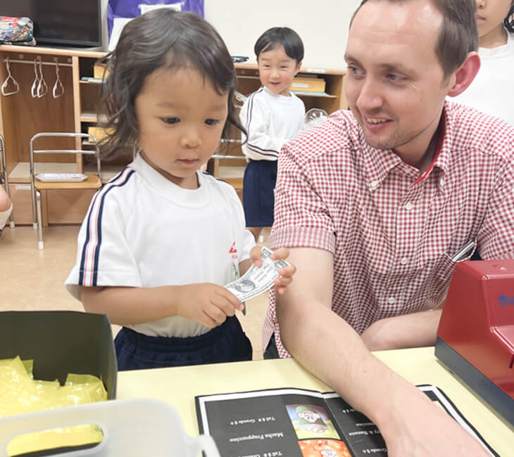 園児と先生がごっこ遊びで一緒に接客をしている