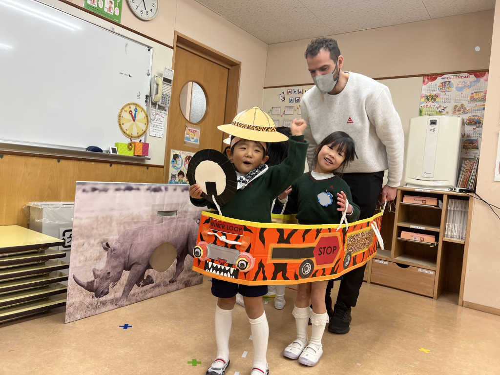 園児と先生がダンボールで作られたバスにのって遊んでいる