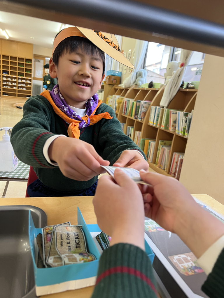 園児がごっこ遊びのお会計でお札を受け取っている