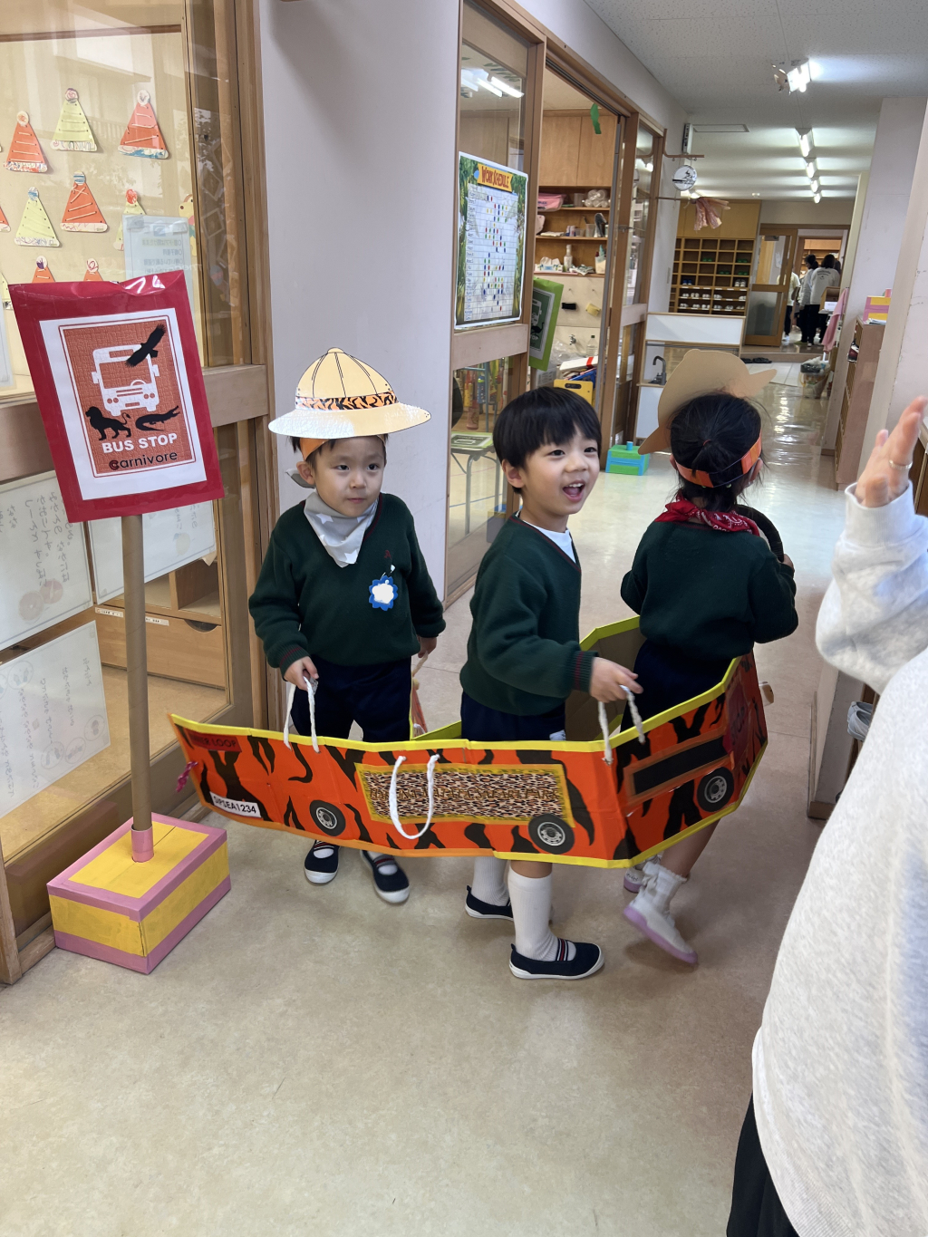 園児が集まってダンボールで作られたバスに乗って遊んでいる