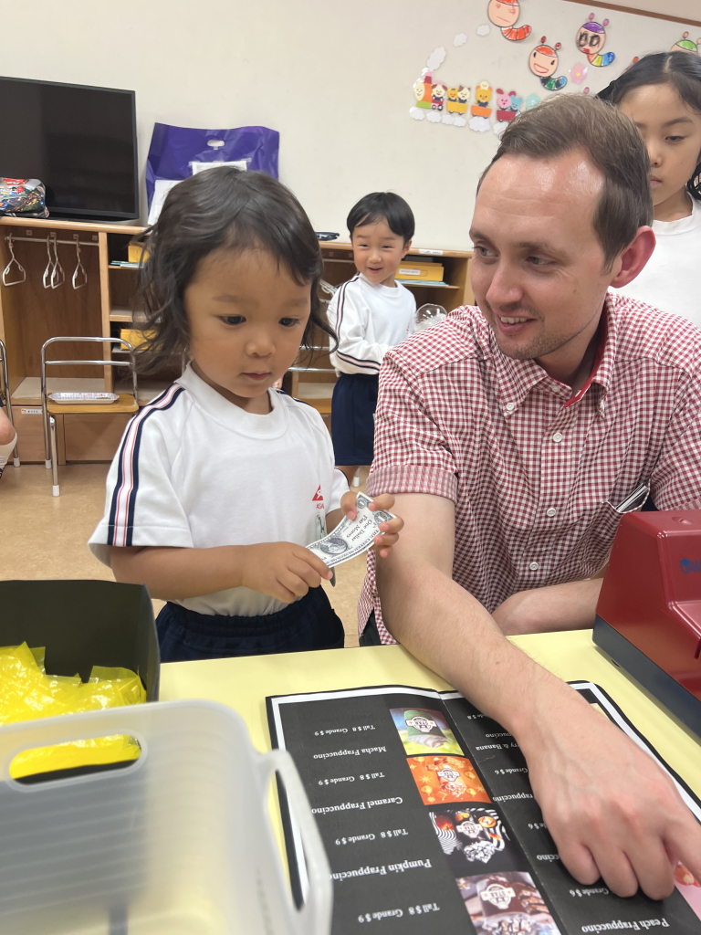 園児と先生がごっこ遊びで一緒に接客をしている